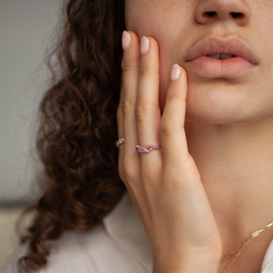 Close-up of a woman's hand with a ring, touching her face.