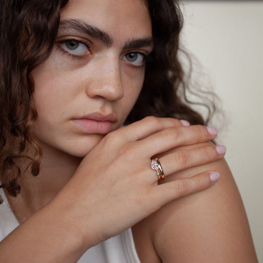 Woman with a ring on her finger, wearing a white tank top.